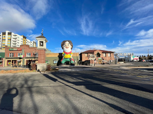 36 feet high, the prospector has green pants, a yellow top, and a red scarf